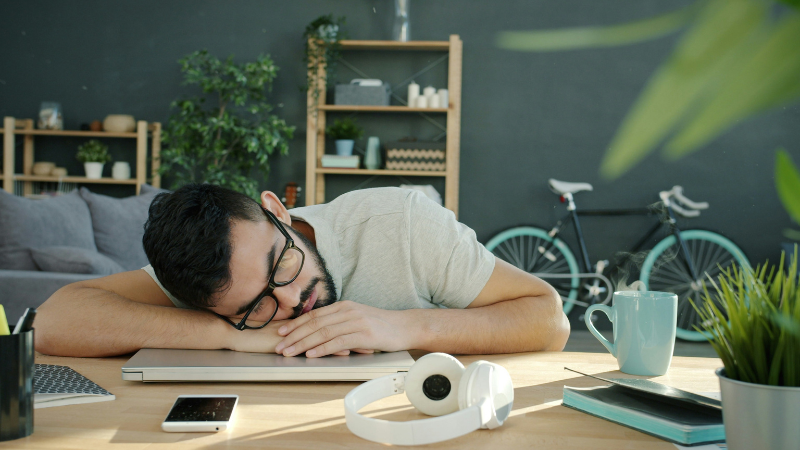 Person feeling tired and sleepy while working at desk showing how lack of sleep affects focus and how to get rid of laziness naturally